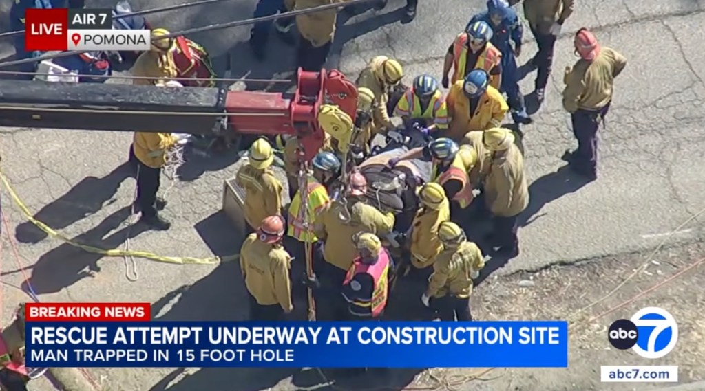 A live aerial shot shows emergency responders rescuing a man from a hole at a construction site in Pomona.