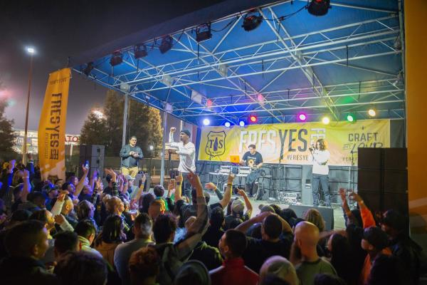 Crowd gathers around stage cheering on performer