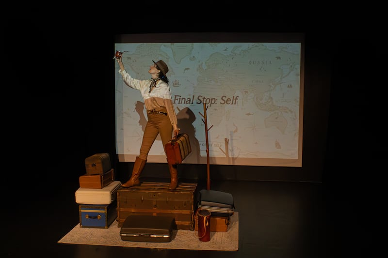 The final scene of the Mate Monologues, where Natasha Nua stands on top of her fractured identity, symbolized through the suitcases that each represent a journey to her past. (Photo courtesy of Mel Skinder)