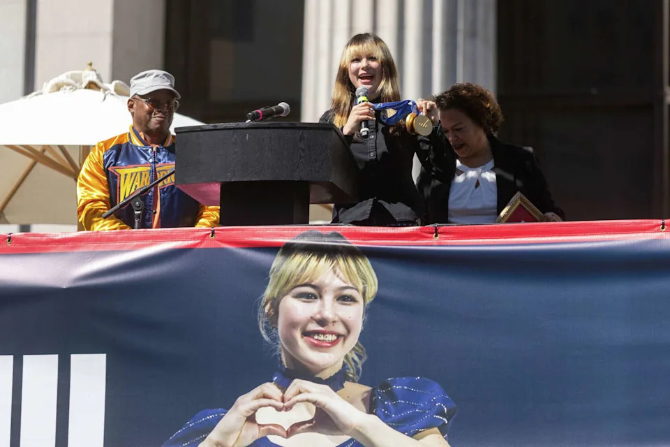 Olympic figure skating gold medalist Alysa Liu holds up her gold medals won at the 2026 Winter Olympics during the Alysa Liu Celebration Rally at Frank Ogawa Plaza in front of Oakland City Hall in Oakland, Calif., on March 12, 2026. (Douglas Zimmerman/SFGATE)