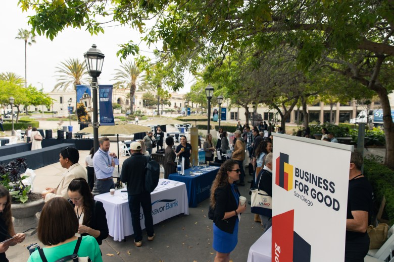 An outdoor event with tables and posters for Business for Good