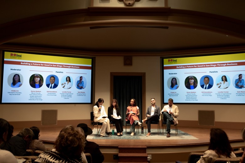 A panel on a stage with a crowd watching