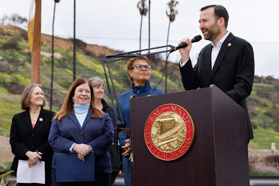 A man speaks behind a lectern as people watch him.