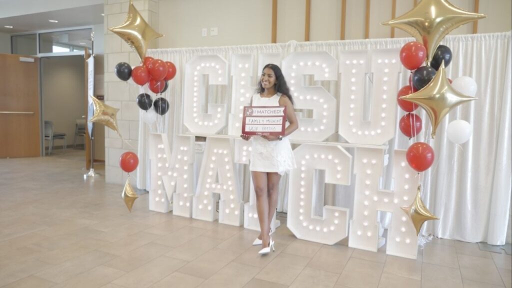A student who was matched in Family Medicine at UCSF Fresno poses in front of a sign at California Health Sciences University in Clovis on Friday's, March 20, 2026, Match Day. (GV Wire/Jahziel Tello)
