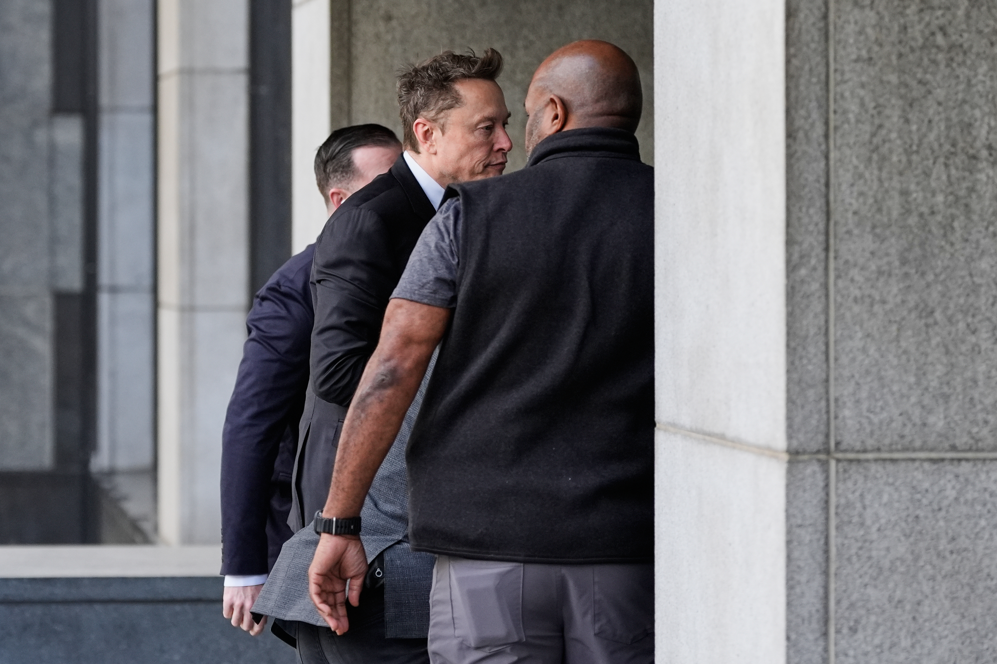 Elon Musk, center, arrives for a Twitter shareholder trial at...
