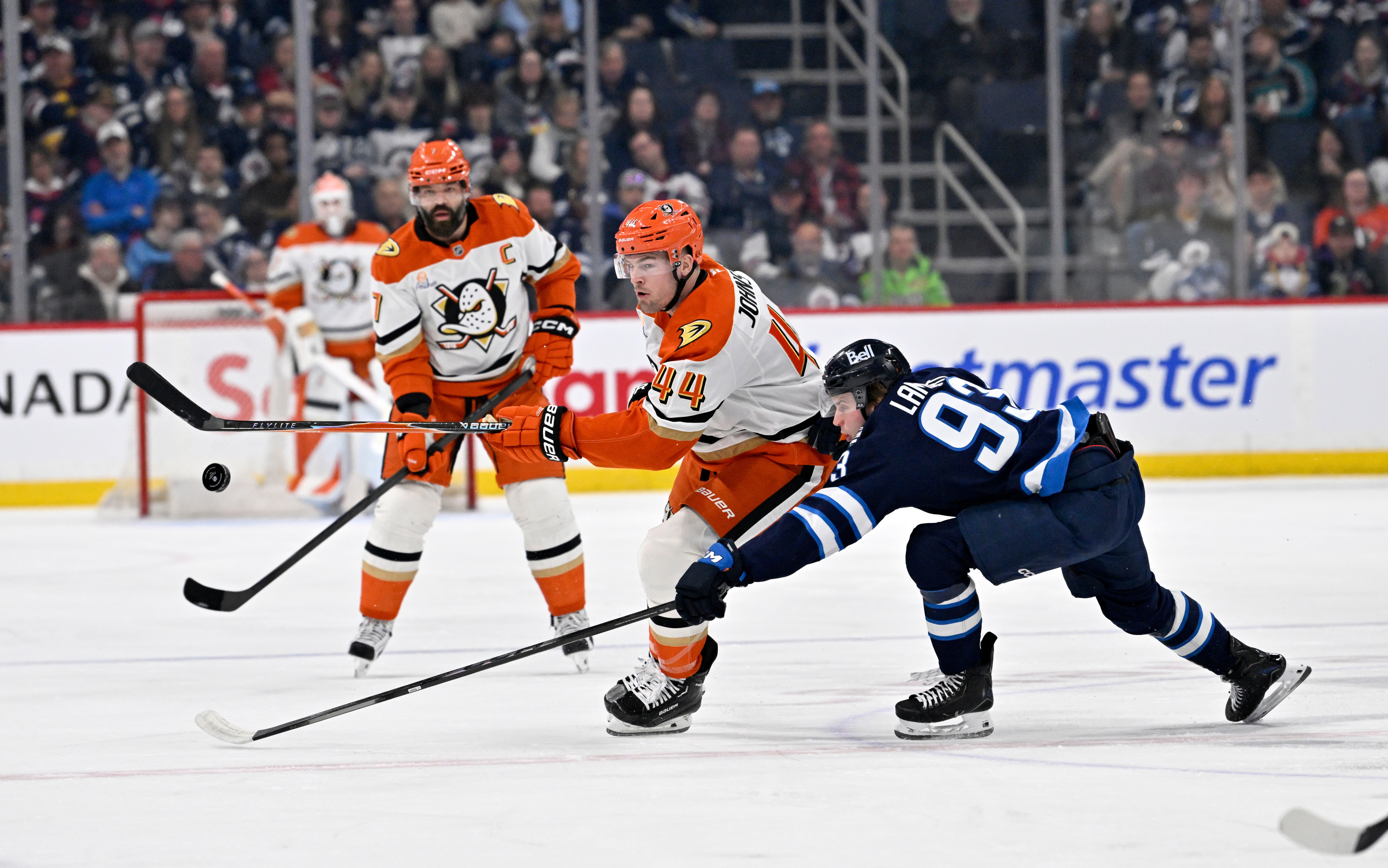 The Ducks’ Ross Johnston (44) chases the bouncing puck as...