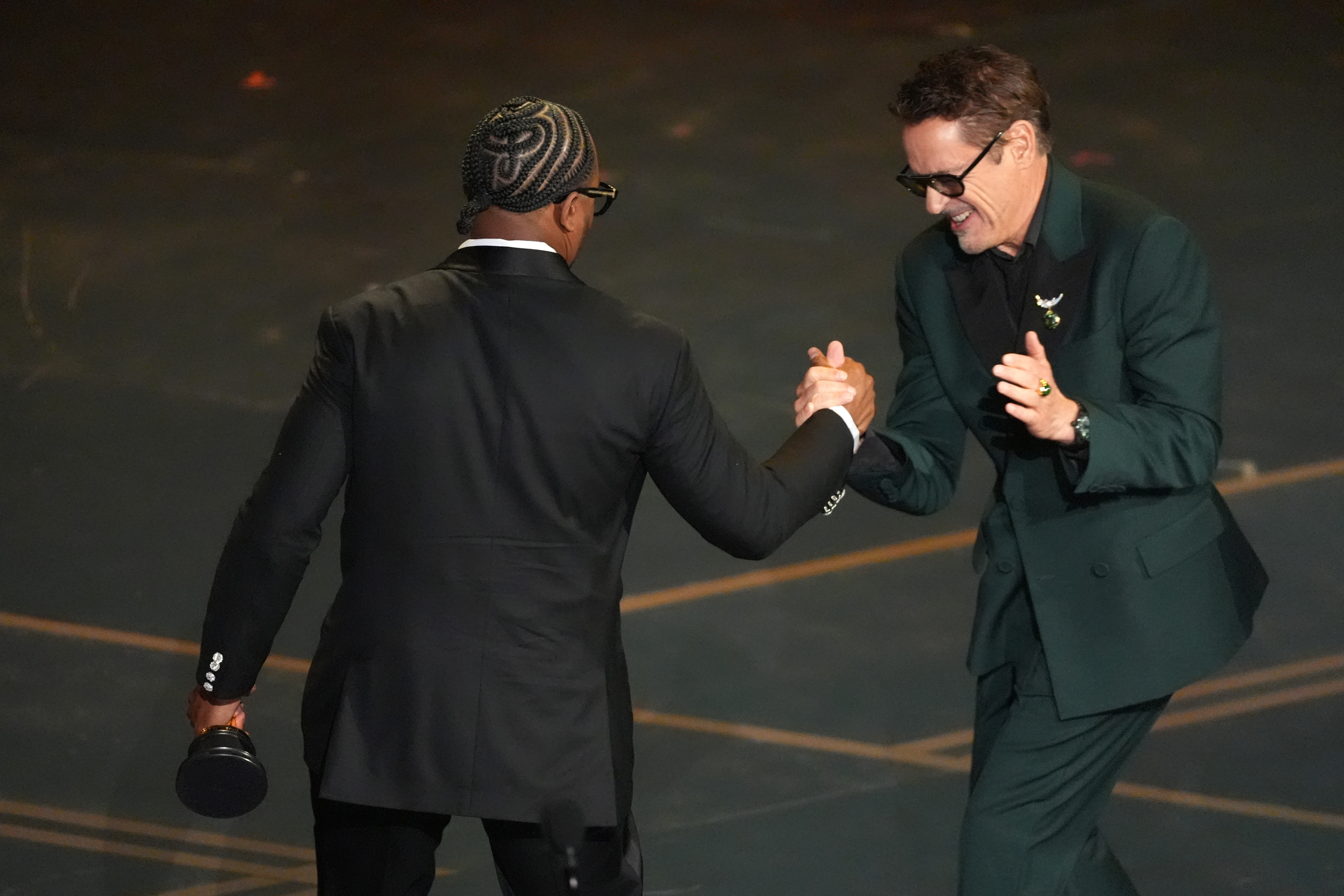Robert Downey Jr., right, congratulates Ryan Coogler for winning the award for writing (original screenplay) for “Sinners” during the Oscars on Sunday, March 15, 2026, at the Dolby Theatre in Los Angeles. (AP Photo/Chris Pizzello)