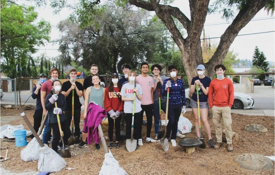 large group of adults with gardening equipment