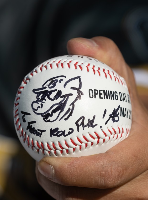 Artist Ken Mitchroney draws a picture of Scrappy, the Oakland Baller mascot, on a fan's ball before the team's home opener against the Ogden Raptors on Tuesday, May 20, 2025, at Raimondi Park in Oakland, Calif. (Karl Mondon/Bay Area News Group)
