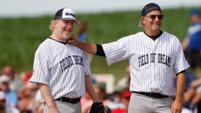 Actors Kevin Costner, right, and Timothy Busfield joke around at first base during a celebrity softball game at the Field of Dreams on Saturday, June 14, 2014, near Dyersville, Iowa. The farm hosted a three-day celebration of the film 