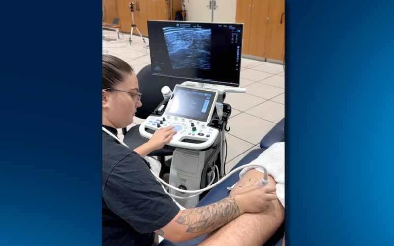 A student performs an ultrasound scan on a research participant's hamstring.