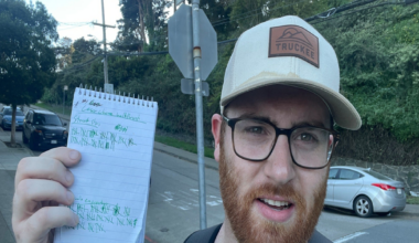 A man with glasses and a beard wears a light green shirt and tan hat while holding a notepad with tally marks at Cesar Chavez and Douglass streets.