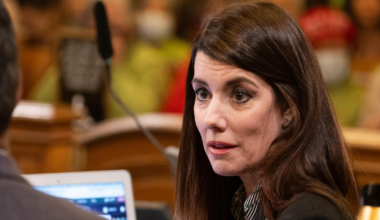 Supervisor Catherine Stefani in her chair talks with another Board of Supervisor during public comment at city hall.