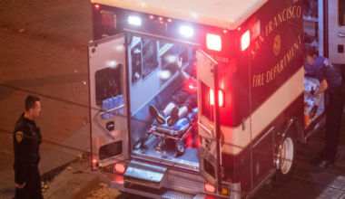 A person lies in an ambulance. Their face is out of frame.