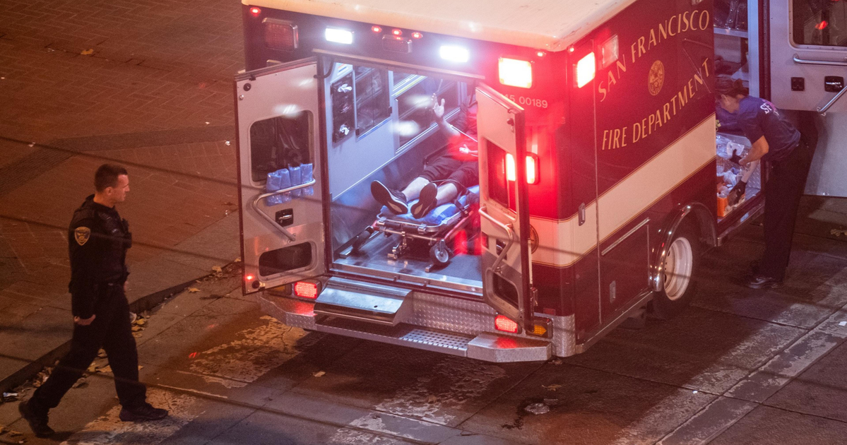 A person lies in an ambulance. Their face is out of frame.