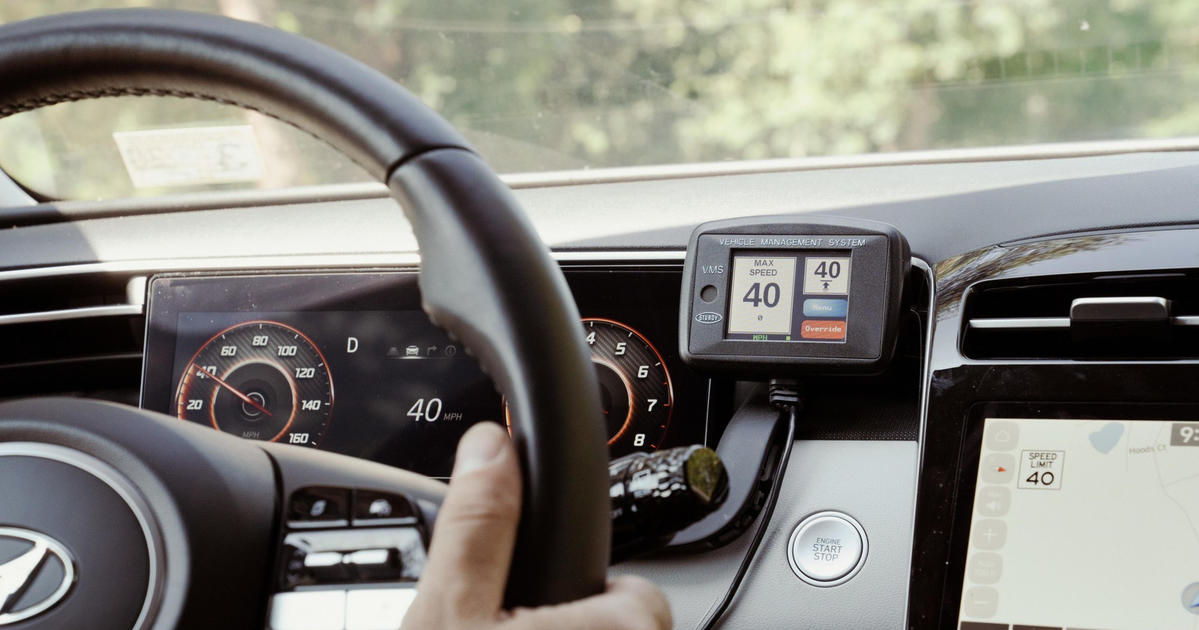 A hand grips a Hyundai steering wheel, the car speed shows 40 mph, a GPS displays a maximum speed of 40 mph, and a push-start button is visible.