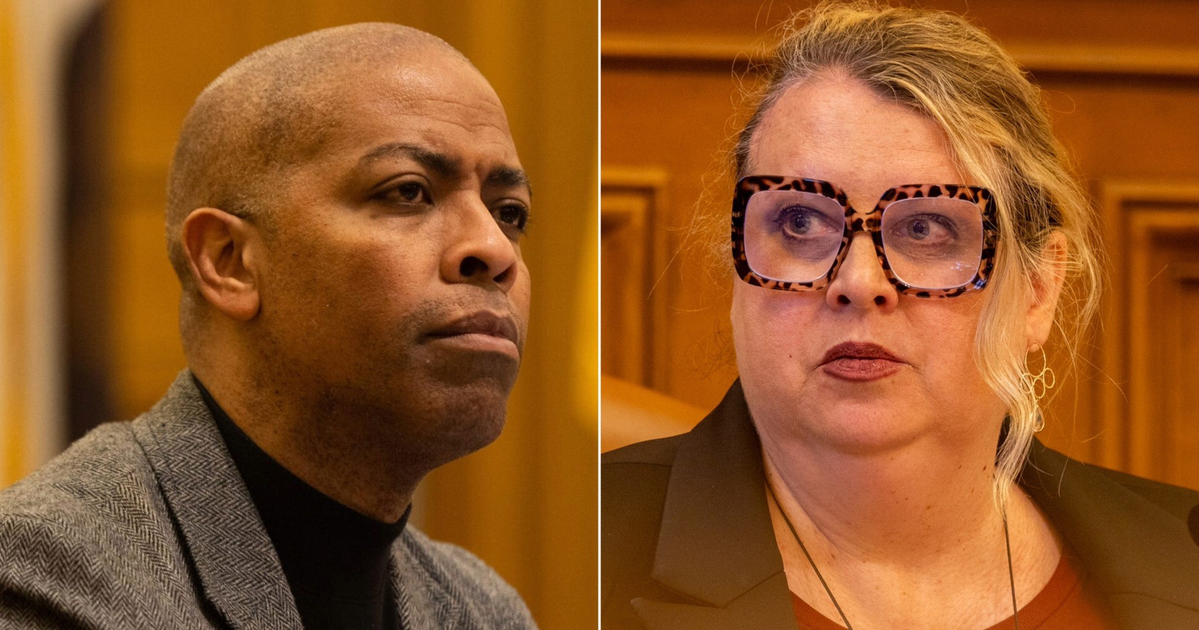 A man in a gray jacket and black turtleneck looks serious, while a woman with large tortoiseshell glasses and a dark blazer looks to the side.