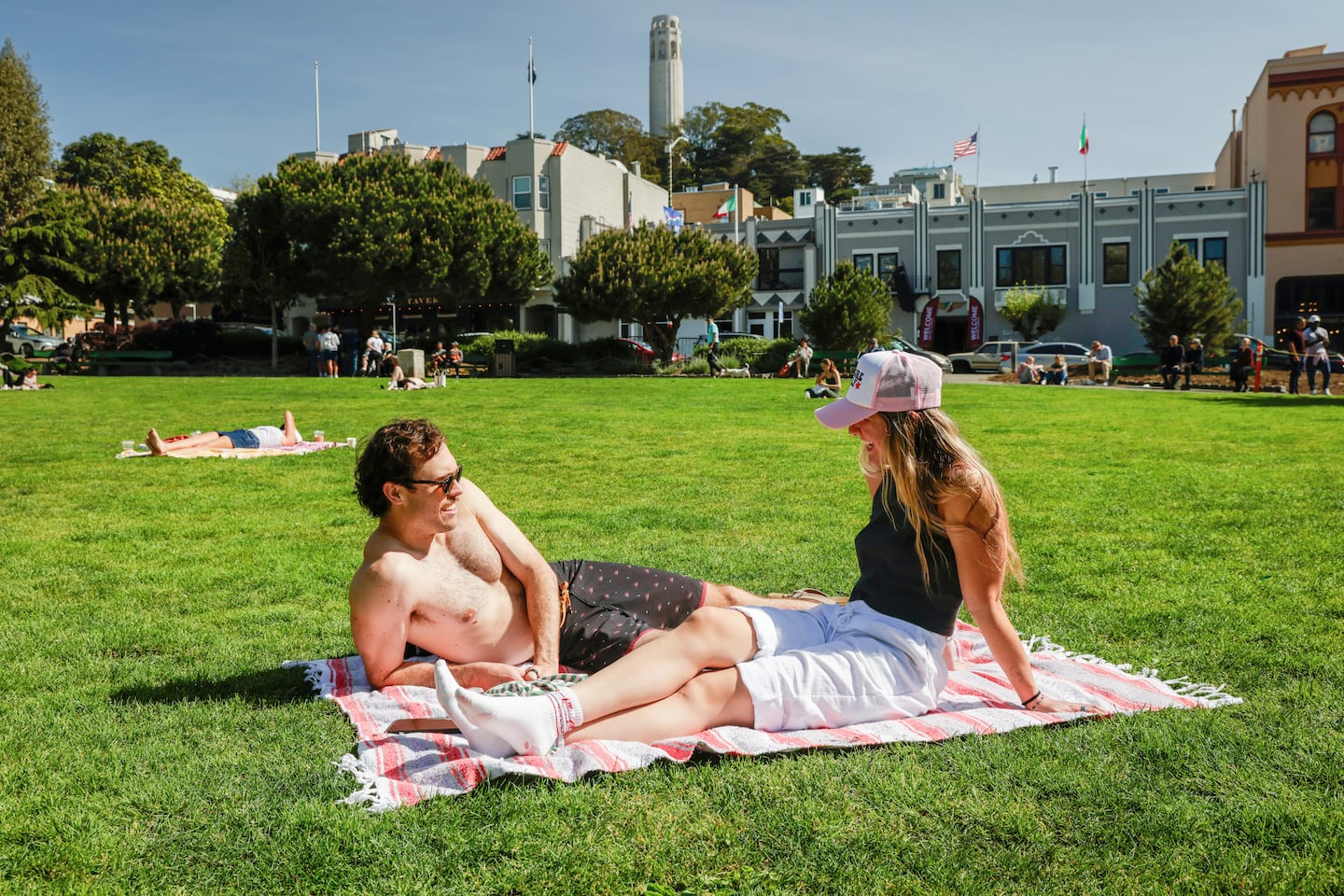 Nick Gardetto, left, and Madi Hirsch lounge in the sun at Washington Square during a heat wave in San Francisco on Sunday.