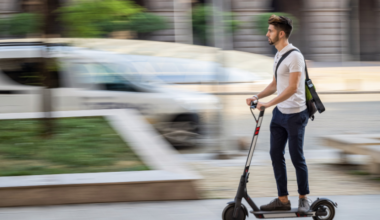 A person rides an e-scooter on the sidewalk