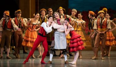 Val Caniparoli—costumed as Don Quixote in breeches, a neck scarf and a curled mustache—stands onstage at the center of a crowd, his arms crossed, smiling slightly. The dancers playing Basilio and Kitri hang adoringly on his arms.