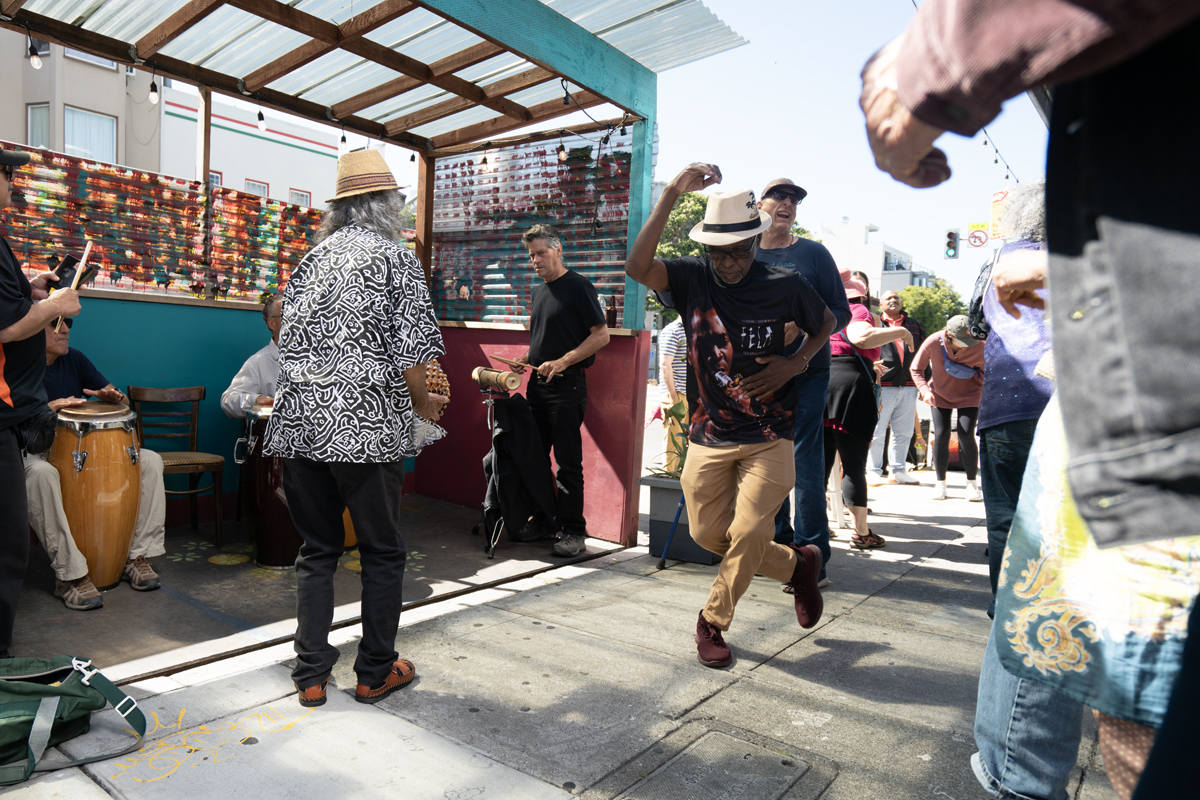 People dancing to live music, mid-day in the street.