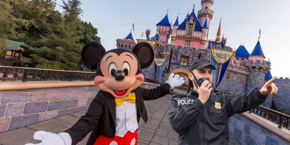 Mickey Mouse in front of Sleeping Beauty Castle in Disneyland with a Police officer next to him as guests go through the gates thanks to the new facial recognition technology involved in a Disney incident.