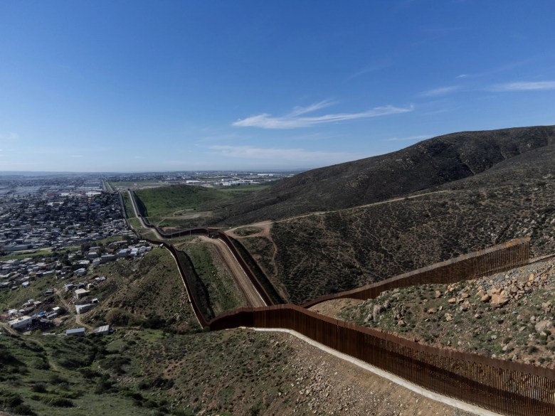 A double wall divides Tijuana from San Diego, with the Pacific Ocean in the backdrop. 