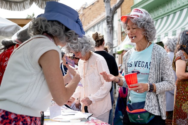 Annie Chan, dressed in full Las Vegas Granny, demands a Bingo Card mark on Park Street during the 2nd Annual GrannyCon in Alameda, Calif., Saturday, March 07, 2026. Chan was there as part of a 50+ Alameda Women's Walking Group. The lighthearted event is a fundraiser for breast cancer research, education and legislation and was formed by a group of moms during the Coronavirus Pandemic of 2020. (Douglas Despres / for the Bay Area News Group)