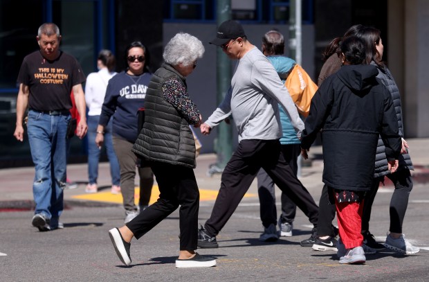Pedestrians cross the Chinatown intersection of Webster and 8th Streets in Oakland, Calif., on Wednesday, March 11, 2026. The Oakland Alameda Access Project launched in March with a goal to enhance connections between Oakland and Alameda, while decreasing traffic volume through Chinatown. (Jane Tyska/Bay Area News Group)