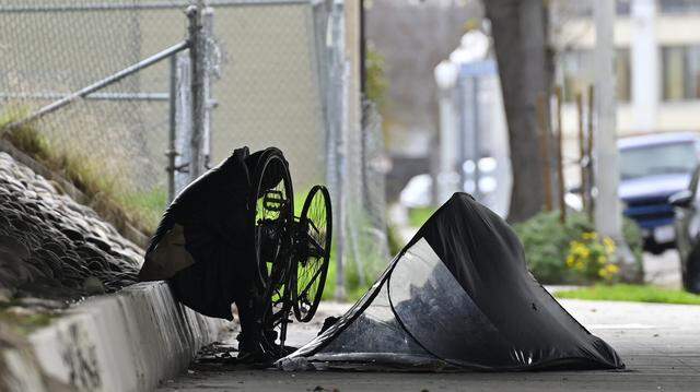 A homeless man works on his bicycle outside his tent underneath Freeway 180 on North Broadway Street Friday, Dec 26, 2025 in Fresno.