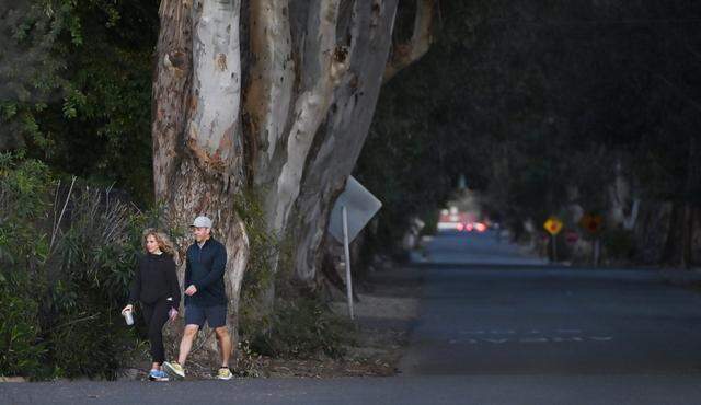 A couple walk onto Palm Avenue, part of the Old Fig Garden nieghborhood, Wednesday, March 4, 2026 in Fresno.
