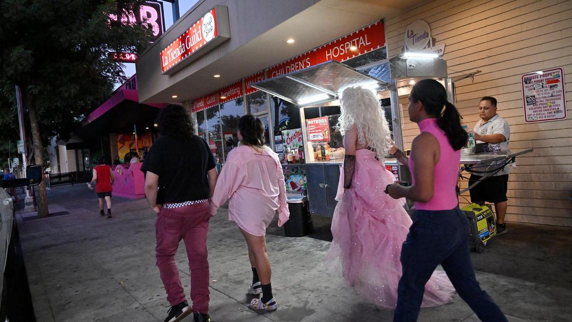 Pedestrians pass Jaime Gómez, a food vendor selling hot dogs on the sidewalk along Olive Avenue in Fresno’s Tower District Wednesday evening, July 19, 2023.