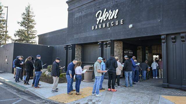 Lunchtime visitors check menus while waiting in line outside Horn Barbecue in Fresno's Granite Park shopping center on Friday, Jan. 23, 2026. The long-anticipated barbecue restaurant opened on Tuesday, Jan. 20.