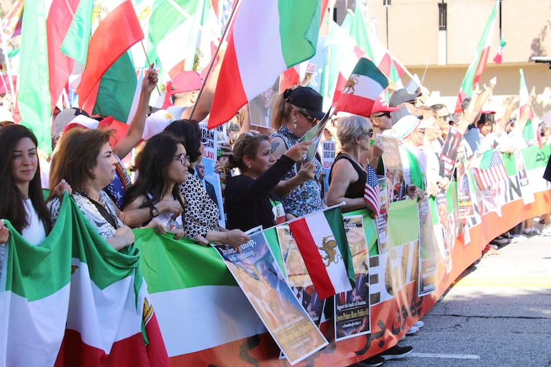 Members of the Iranian American community march down Wilshire Boulevard, chanting support for President Trump and Reza Pahlavi through megaphones as others beat drums. (Photo by Charlotte Calmès)