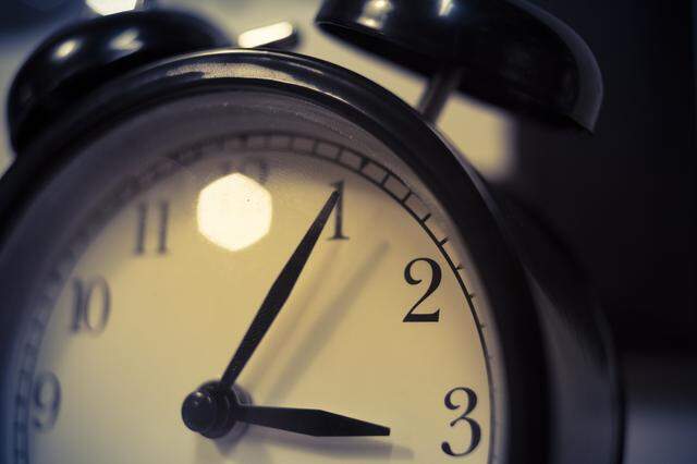The stock image shows a close-up view of an old-fashioned alarm clock. The minute hand is on 1 and the hour on 3.