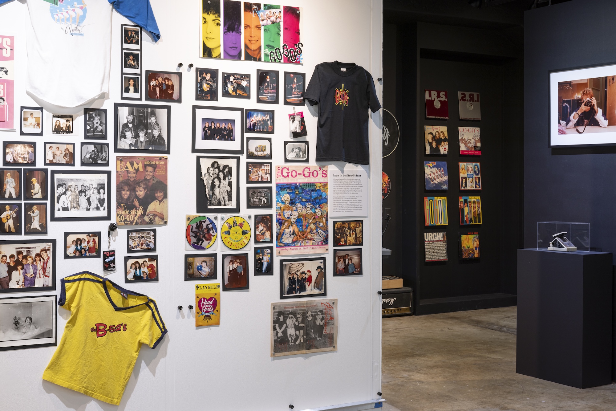 A gallery wall covered in photos, posters, t-shirts and other ephemera, all about The Go-Go’s.