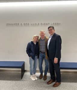 Jennifer and Bob Hagle pose with David Faigman in front of a wall bearing their name.