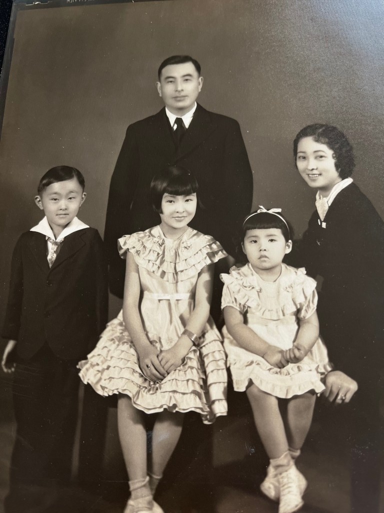 A black-and-white family portrait with two adults and three children in formal attire.