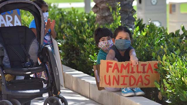 Children hold signs calling for the unification of separated immigrant families.