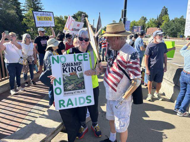 Susan Cunningham of the Folsom Area Democratic Club shows a sign depicting President Donald Trump during a No Kings rally Saturday morning as demonstrators prepared to march across the Lake Natoma Crossing bridge in Folsom.