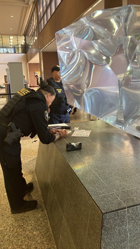 Two uniformed officers at a stone countertop with a reflective sculpture.