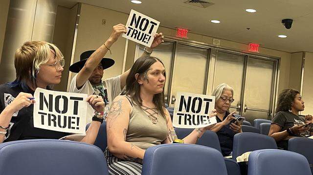 Members of the advocacy group Fresnans for a People’s Budget hold up signs that say “Not True!” at Fresno police departments first ever public engagement meeting on its annual military equipment use report.