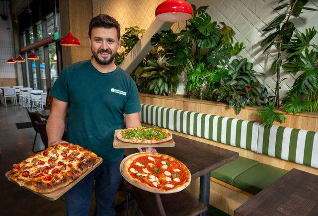 Bambina’s Pizza and Pasta owner Juanes Ramazzini holds three styles of pizzas: pinsa, Sicilian style and “Bambina style,” on Oct. 10, 2024.