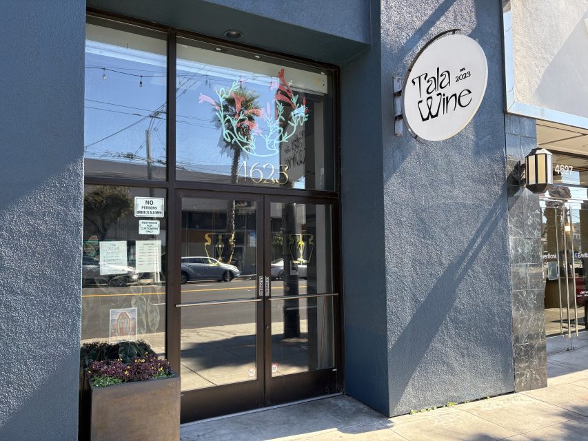 Storefront of Tala Wine with large glass doors, a decorative window display, and a round white sign showing the business name and street number 1625.