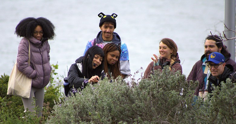 A group of young people inspect a plant