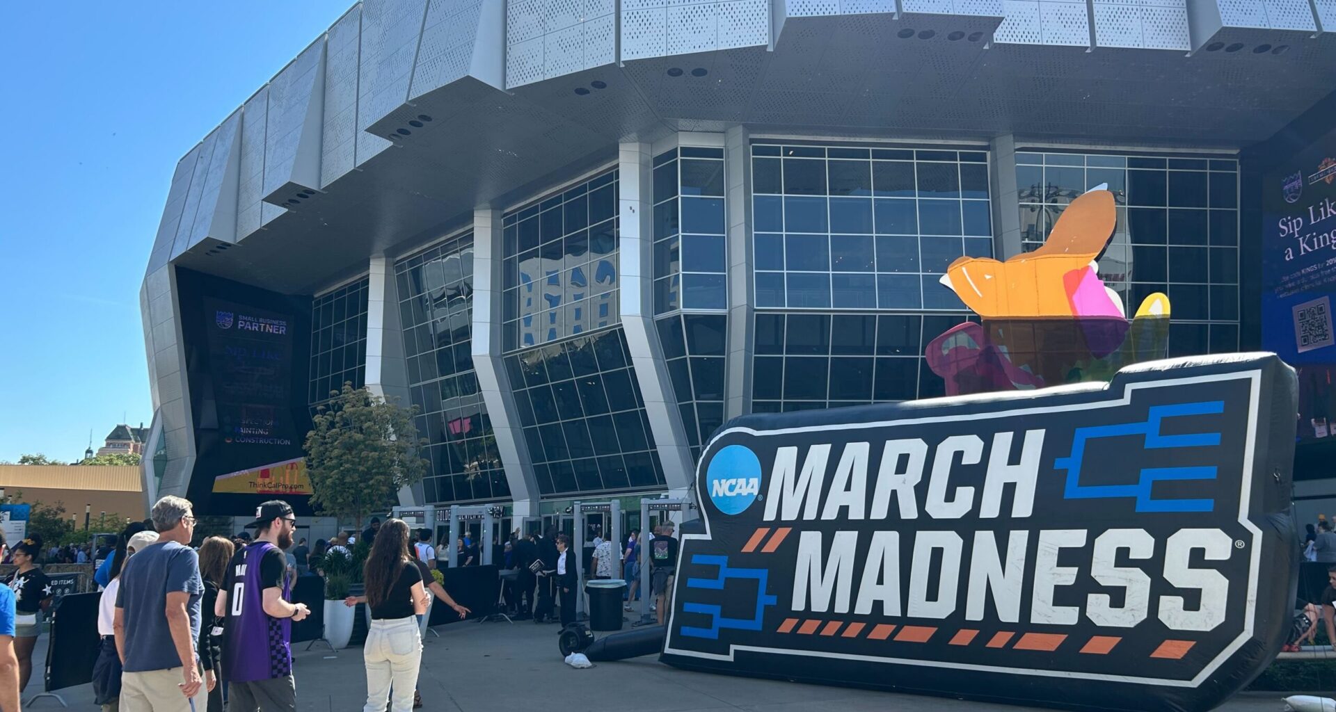 Sports fans line up outside Golden 1 Center and March Madness signage