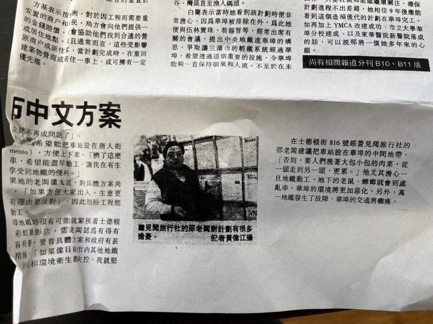 A newspaper page with Chinese text and a black-and-white photo of a person sitting in front of display boards.