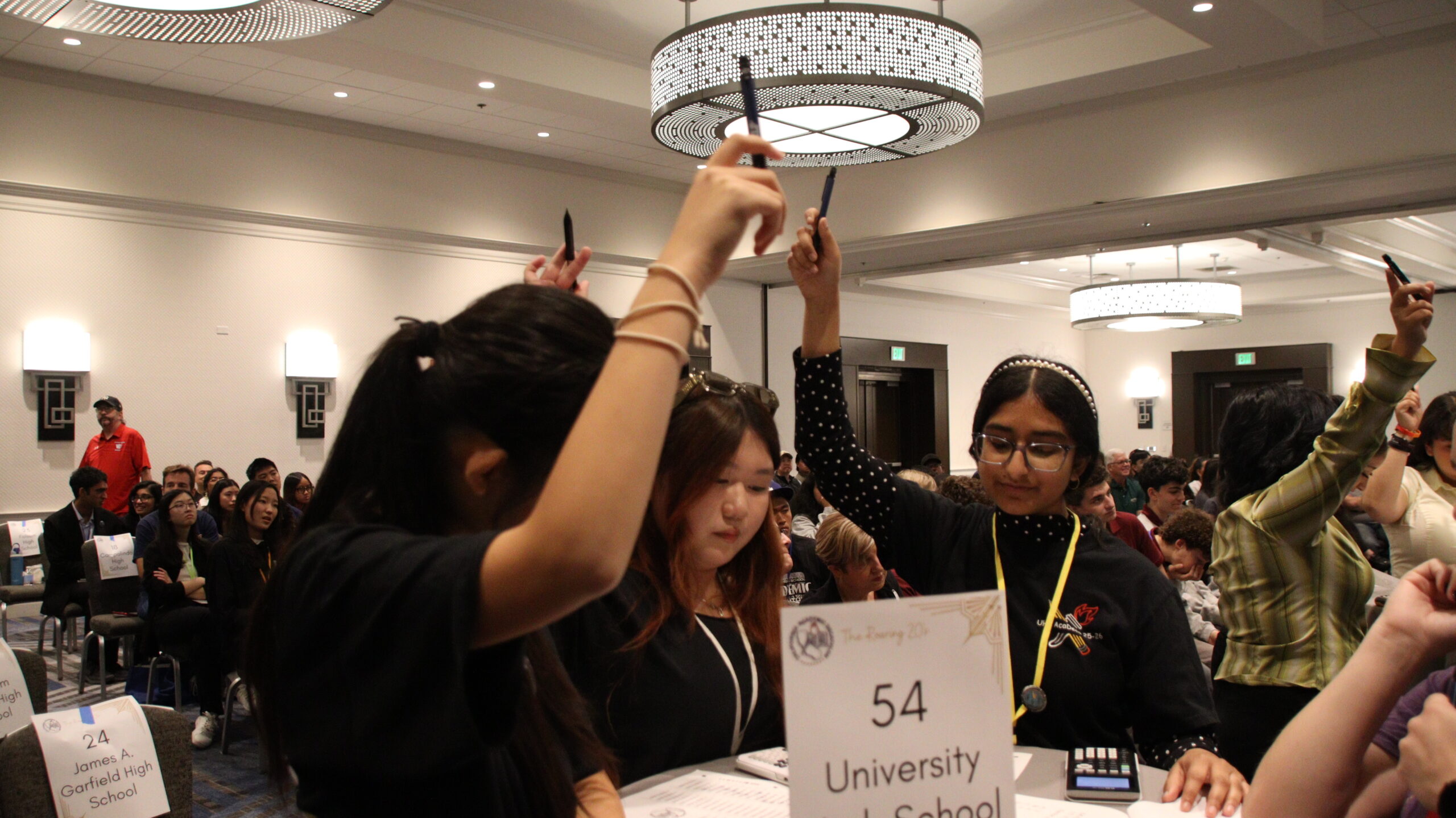 University High School students raise pens while participating in the Super Quiz event during the Academic Decathlon competition.
