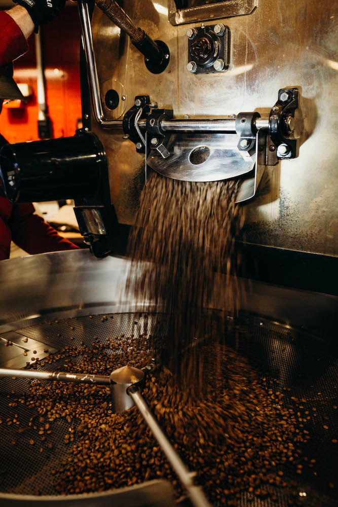 Doug Bond checking beans in the coffee roasting machine. (Photo by Leo Hollen Jr)