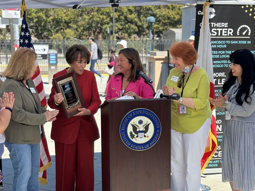 Four women stand behind a lectern with Congresswoman Anna Eshoo